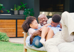 Happy veteran family relaxing in the backyard of a sunlit home, lifestyle shot