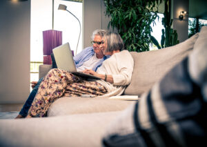 Senior veteran and spouse sitting together looking at financial planning documents on a laptop